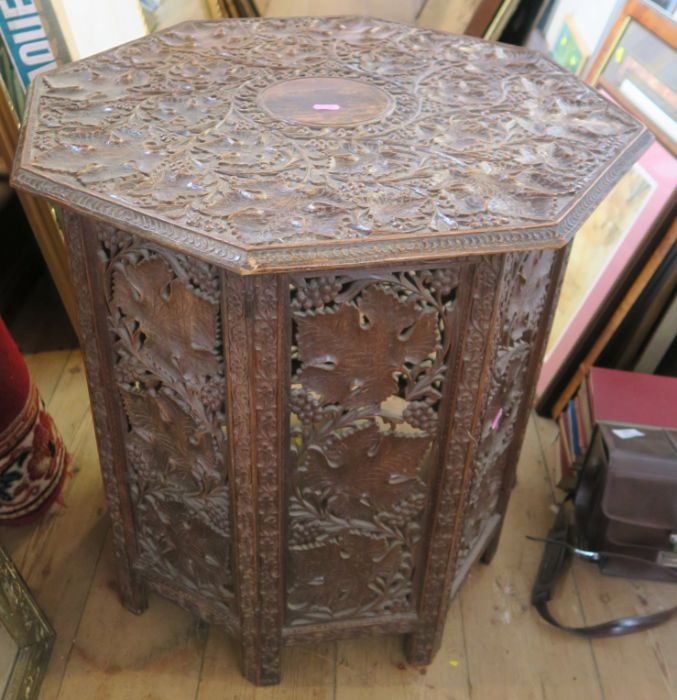 A carved Eastern octagonal table, with folding base, diameter 24ins, height 25ins