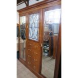 A Warings mahogany wardrobe, with a glazed door over drawers, flanked by mirrored doors, the whole
