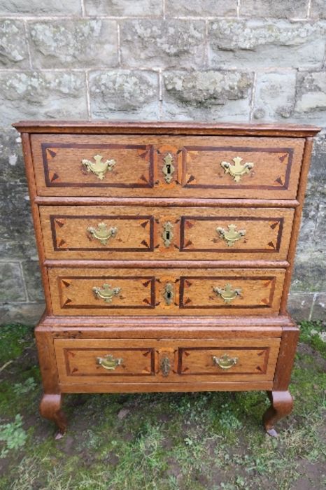 An 18th century design small oak chest on stand, with three drawers, having inlaid and cross