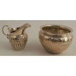 A silver cream jug, together with matching sugar bowl, with embossed band of flowers and scrolls,