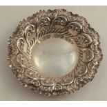 A silver dish, of shaped circular form, with embossed border, having an inscription to the centre,