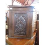 A carved oak corner cupboard, the door opening to reveal shelves, width 23ins x height 24ins