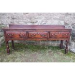 An antique oak/elm dresser base, fitted with three drawers, raised on front turned legs, width 79ins