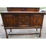 An Edwardian oak sideboard, fitted with cupboards and applied decoration, raised on turned legs,