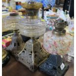 Three oil lamps, with pierced metal bases and glass reserves