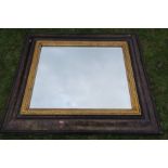 An Eastern design cushion framed mirror, with bevelled plate, 23ins x 29ins