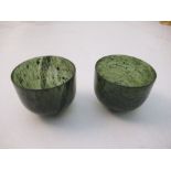 A pair of spinach jade wine cups, raised on a turned base, height 1.5ins