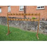 A wooden free standing coat rack, with two levels of hooks, height 66ins x width 90ins