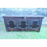 An 18th century oak coffer, with plain rising lid, having three arcaded panels to the front, width