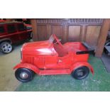 A red swing pedal car, with solid rubber tyres, 32” x 18”