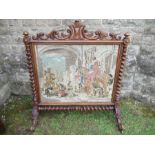 A large 19th century tapestry fire screen, with carved top and raised on barley twist supports,