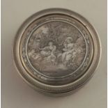 A silver circular box, the pull off cover engraved with figures in a garden with sheep after F