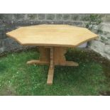 An octagonal oak dining table, with concave borders, raised on cross frame legs, with outswept