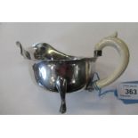 A silver sauce boat, having ivory handle and raised on pad feet, rubbed hallmark, length 6ins