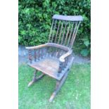 A primitive spindle back rocking chair, with solid seat