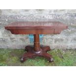 A 19th century mahogany fold over card table, raised on a turned fluted column, terminating in a
