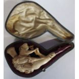 A cased Meerschaum pipe, carved with a semi naked female and another female blowing a pipe