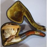 A cased Meerschaum pipe, carved with a woman's head, wearing a hat