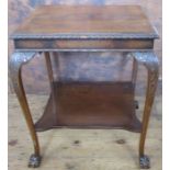 A mahogany rectangular two tier table, with carved decoration and raised on claw and ball feet,