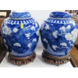 A pair of Oriental covered blue and white ginger jars, decorated with flowering prunis, on wooden