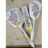 A three piece silver and enamel dressing table set, decorated with flowers