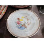 An Oriental shallow dish, decorated in the famille rose pattern with flowers and jars, chip to