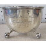 A silver bowl, with hammered finish and engraved with a name and date, raised on three scroll