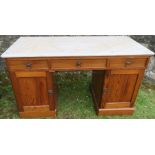 An Edwardian pine and marble topped desk/wash stand, fitted with three frieze drawers and