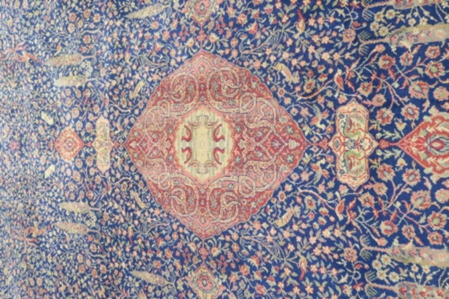 A large Eastern design rug, having a blue ground to a red border, decorated with foliage and - Image 2 of 4