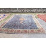 A large Eastern design rug, having a blue ground to a red border, decorated with foliage and