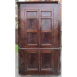 A free standing late Georgian mahogany corner cupboard, of double height, with panelled doors, to