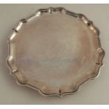 A silver salver, with ogee border, raised on three scroll feet, London 1957, weight 9oz, diameter