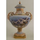 A Royal Worcester covered pedestal vase, decorated with flying swans by C H C Baldwyn, on a powder