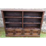 A dark oak bookcase, fitted with adjustable shelves over cupboards, 55.5ins x 12ins, height 42ins