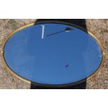 An oval wall mirror, with gold coloured metal frame and bevelled plate, overall dimensions 31.5ins x