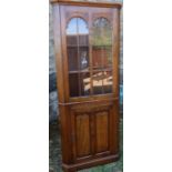 A reproduction oak floor standing corner cupboard, with glazed upper section and cupboard base,