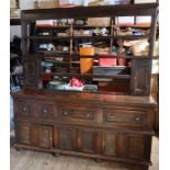 An antique oak dresser, the base fitted with three short drawers over cupboards, with open rack over