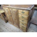 A pine chest, fitted two cupboard doors, flanked to the righthand side by six short drawers, width