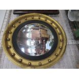 A circular convex wall mirror, the gilt frame with ball decoration and black slip, overall