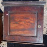 An antique oak wall cupboard, the panelled door opening to reveal shelves and a small drawer,