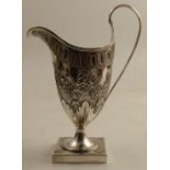 A Georgian silver helmet shaped cream jug, with embossed decoration, raised on a pedestal with