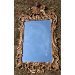An antique gilt framed wall mirror, the rectangular plate with leaf and scroll frame, overall
