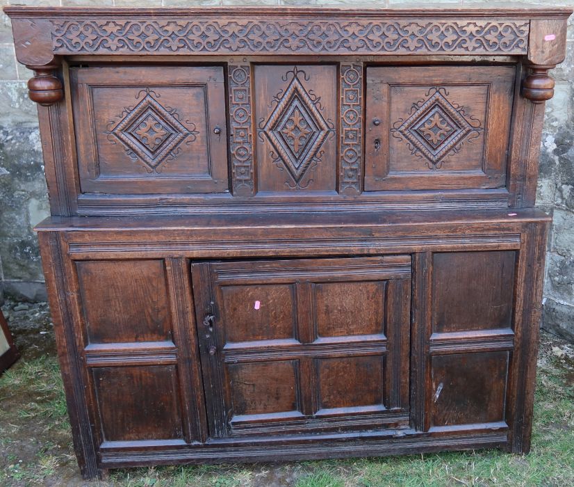 An antique oak court cupboard, fitted with two cupboards to the upper section, and a central