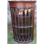 A mahogany barrel front corner cupboard, with fancy glazed door, opening to reveal three shelves,
