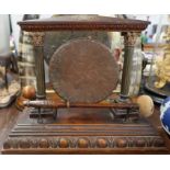 A 19th century oak table top dinner gong, the metal gong suspended in a frame supported by