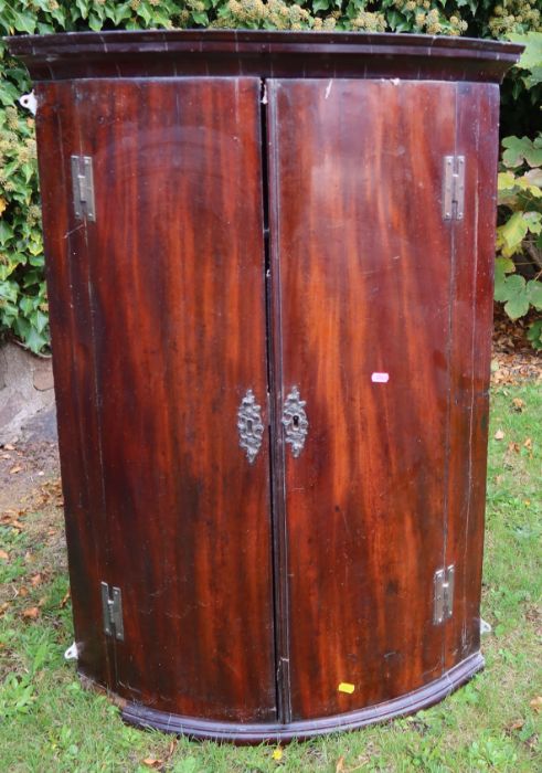 A 19th century mahogany barrel front corner cupboard, fitted with shelves, height 39.5ins, width