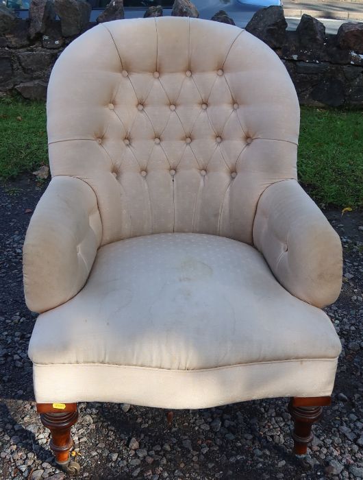 A Victorian spoon button back armchair, raised on short turned front supports