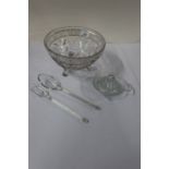 A glass salad bowl and servers, together with a lemon squeezer