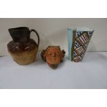 A stoneware jug, with metal collar, together with a vase and a wall mask,