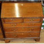 An Antique oak bureau, the fall flap opening to reveal pigeon holes and drawers, over two short over
